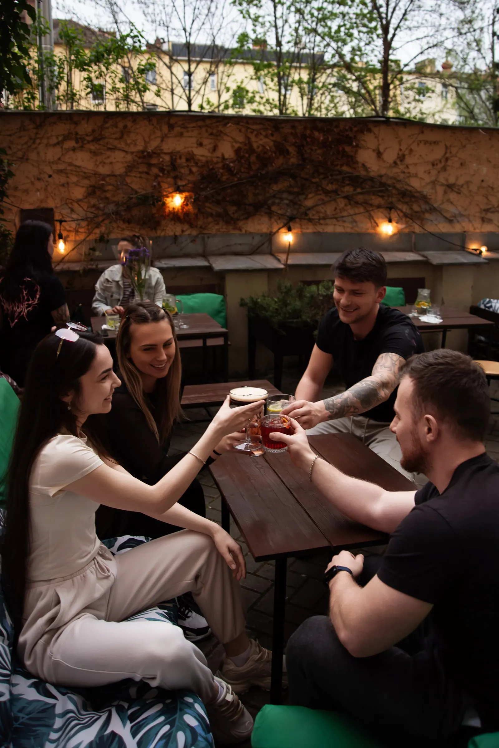 Přátelé na zahrádce baru The Place pod světelnými řetězy